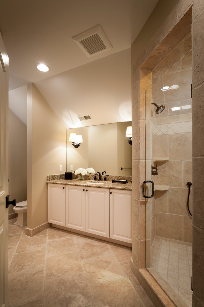 Mid-sized transitional 3/4 bathroom in Detroit with a drop-in sink, shaker cabinets, white cabinets, granite benchtops, a curbless shower, a one-piece toilet, brown tile, stone slab, beige walls and limestone floors.