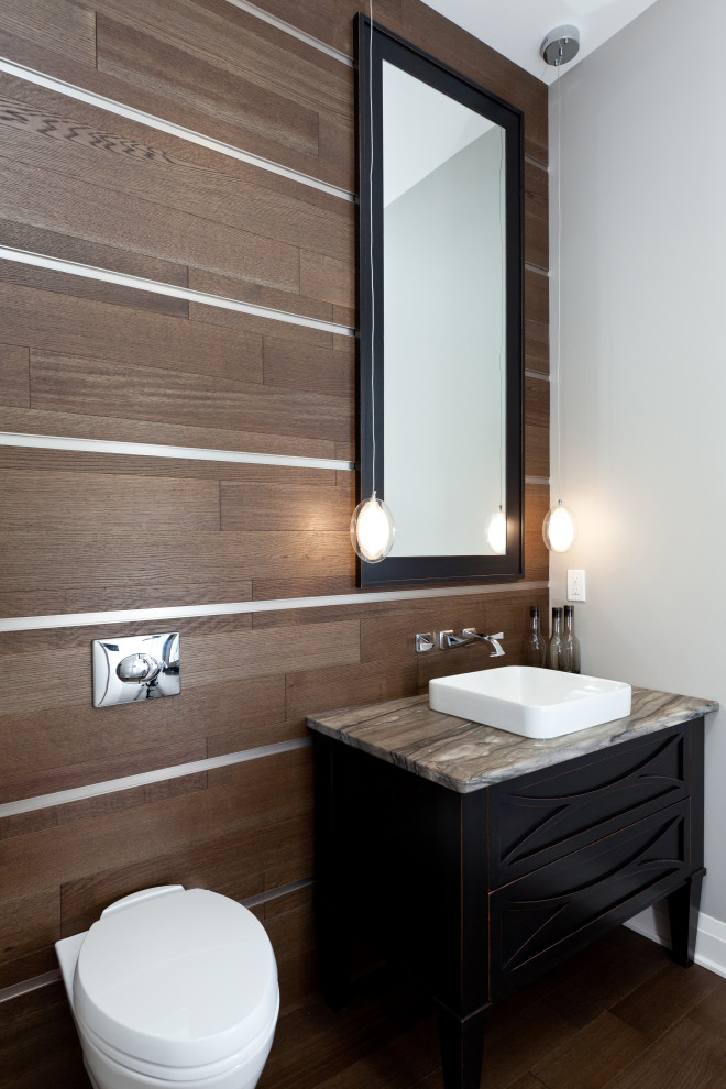 Small transitional powder room in Toronto with shaker cabinets, dark wood cabinets, a wall-mount toilet, beige tile, beige walls, medium hardwood floors, a vessel sink, quartzite benchtops, brown floor, grey benchtops, a built-in vanity and wood walls.
