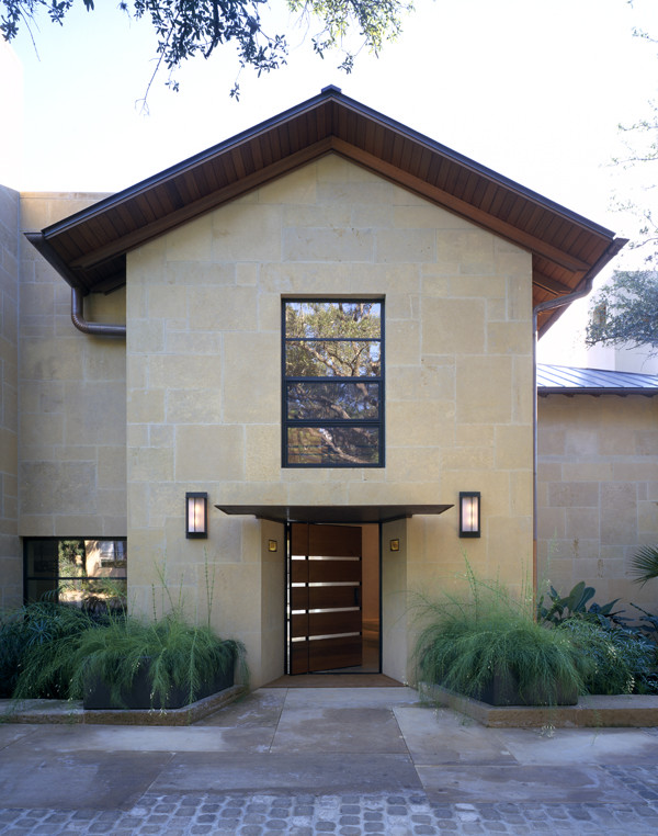 This is an example of a large contemporary two-storey beige exterior in Austin with stone veneer and a gable roof.