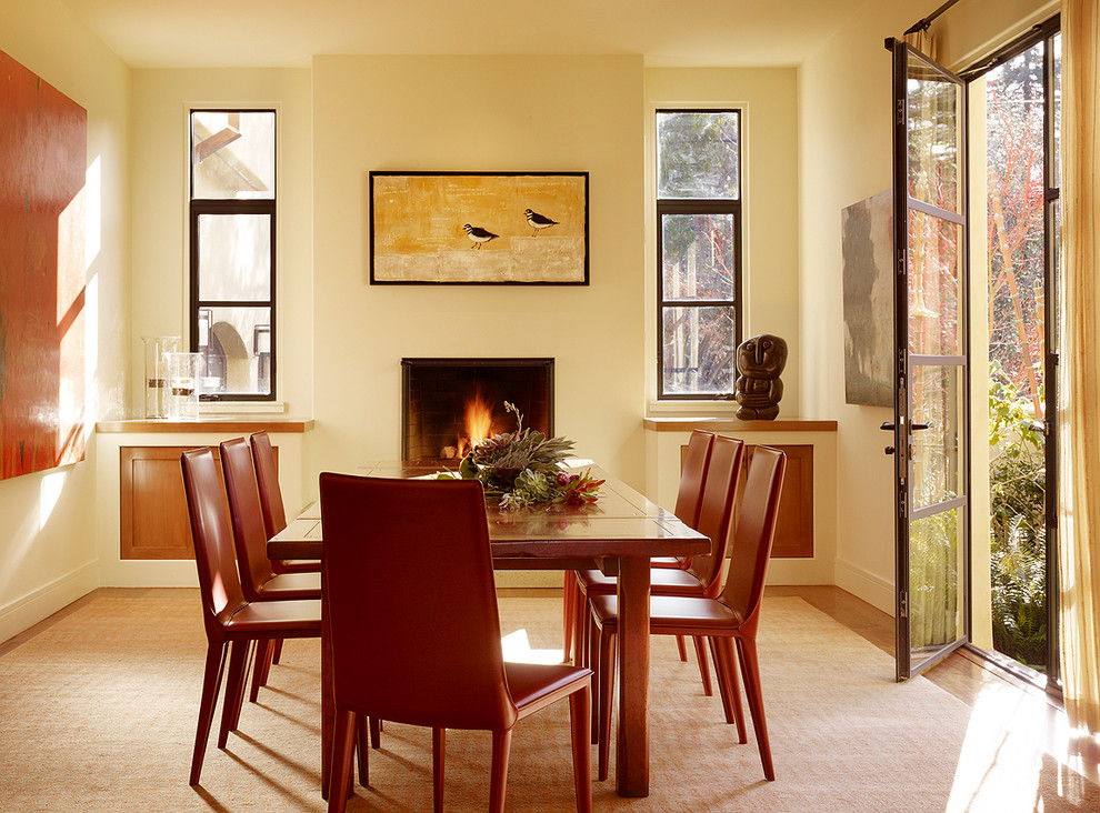 Design ideas for a modern dining room in San Francisco with beige walls, light hardwood floors and a standard fireplace.