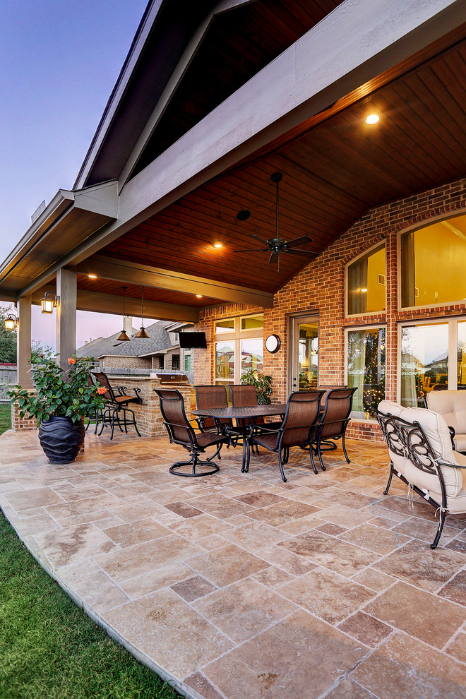 This is an example of a mid-sized traditional backyard patio in Houston with an outdoor kitchen, tile and a roof extension.