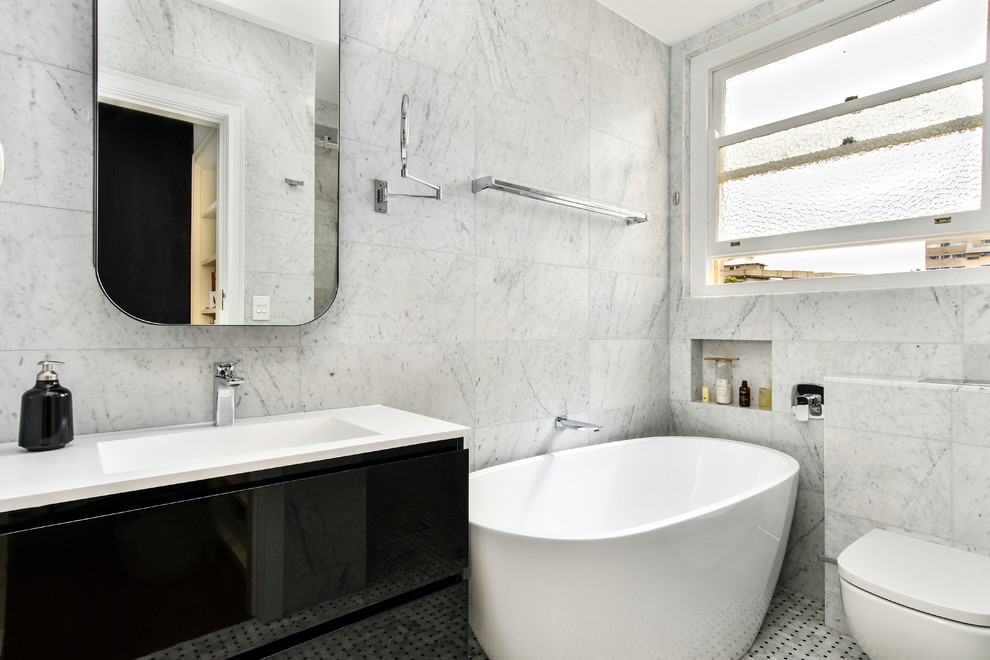 Photo of a small contemporary bathroom in Sydney with distressed cabinets, a freestanding tub, an alcove shower, a wall-mount toilet, multi-coloured tile, grey walls, mosaic tile floors and a sliding shower screen.