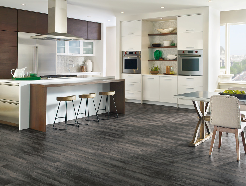 Example of a mid-sized transitional l-shaped vinyl floor and gray floor eat-in kitchen design with an undermount sink, flat-panel cabinets, white cabinets, solid surface countertops, gray backsplash, mosaic tile backsplash, stainless steel appliances and an island