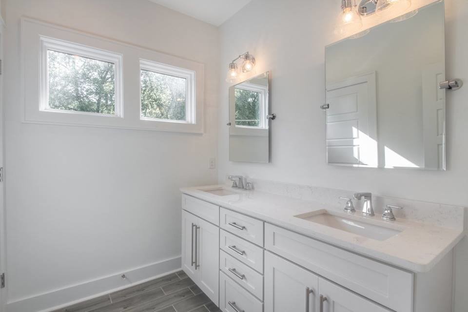 Photo of a mid-sized transitional 3/4 bathroom in Nashville with shaker cabinets, white cabinets, white tile, porcelain tile, white walls, porcelain floors, an undermount sink and quartzite benchtops.