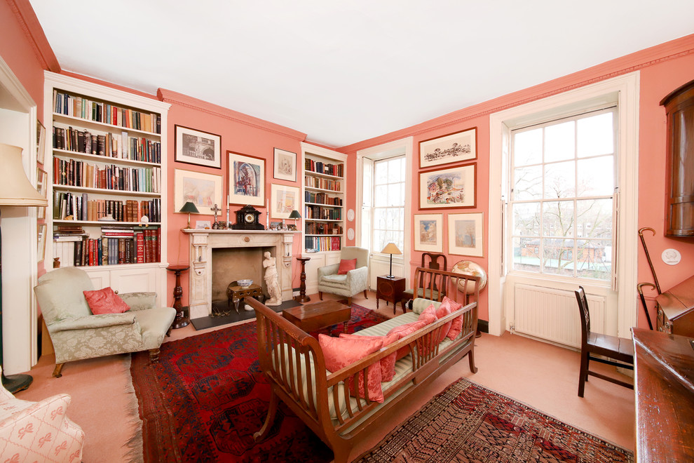 This is an example of a mid-sized traditional enclosed living room in London with pink walls, no tv, a library, a standard fireplace and pink floor.