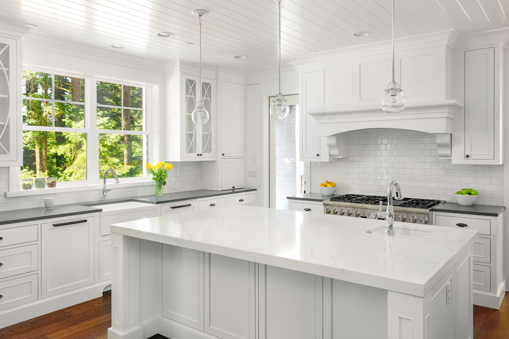 Inspiration for a large country u-shaped eat-in kitchen in DC Metro with a farmhouse sink, recessed-panel cabinets, white cabinets, quartz benchtops, white splashback, subway tile splashback, panelled appliances, dark hardwood floors, with island, brown floor and grey benchtop.