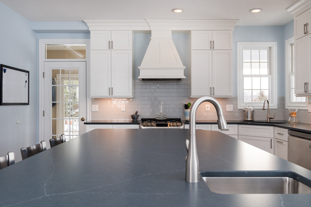 Inspiration for a large transitional u-shaped medium tone wood floor and brown floor eat-in kitchen remodel with an undermount sink, shaker cabinets, white cabinets, quartz countertops, white backsplash, ceramic backsplash, stainless steel appliances, an island and blue countertops
