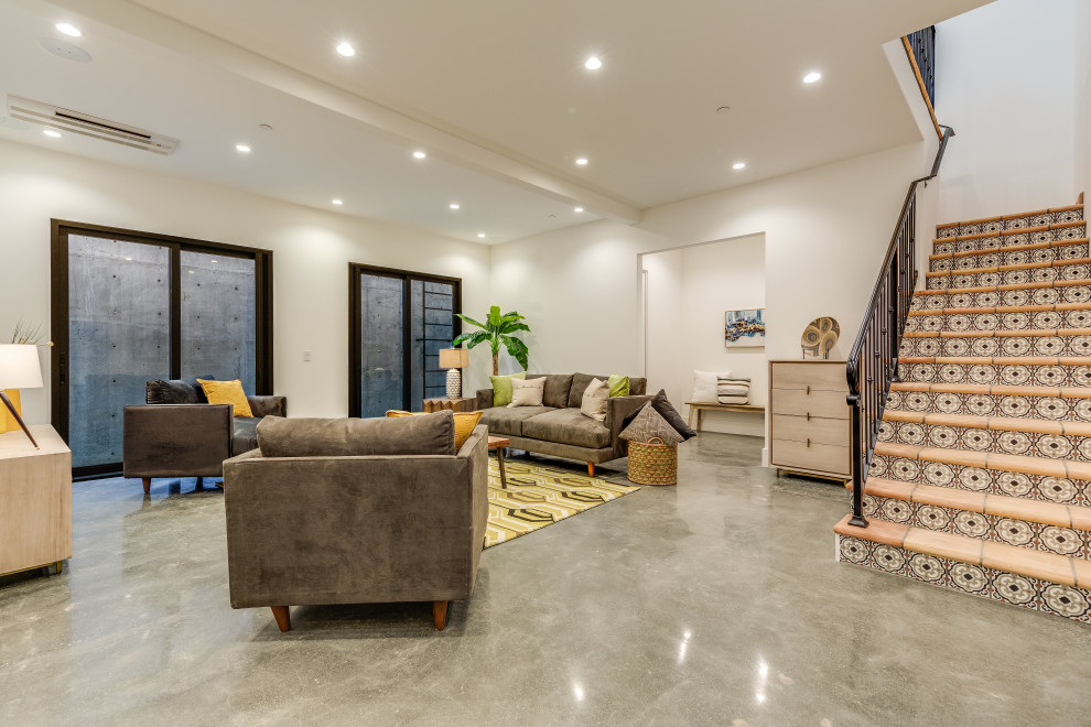 This is an example of a large mediterranean walk-out basement in San Francisco with white walls, concrete flooring and grey floors.