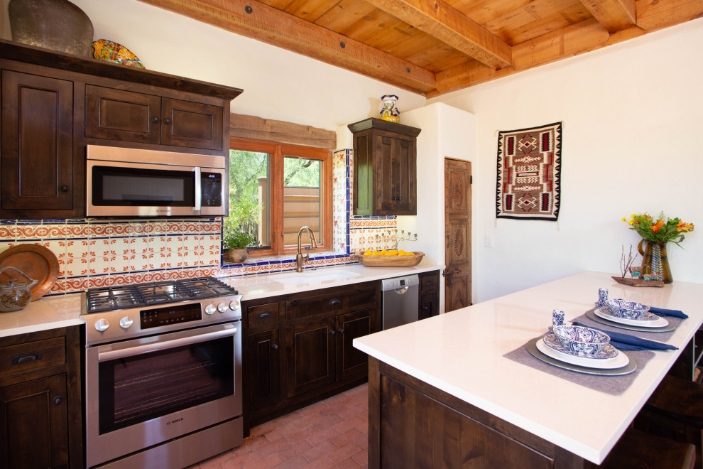 Inspiration for a small country galley kitchen in Phoenix with an undermount sink, shaker cabinets, dark wood cabinets, quartz benchtops, multi-coloured splashback, cement tile splashback, stainless steel appliances, brick floors, with island, beige benchtop and wood.