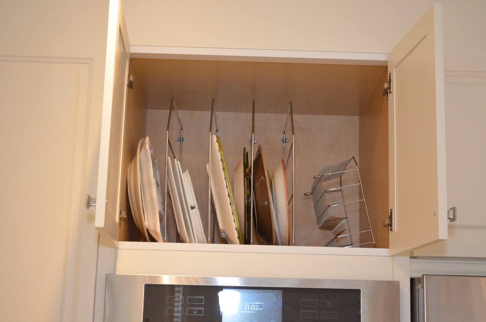 Mid-sized transitional l-shaped porcelain tile enclosed kitchen photo in Toronto with an undermount sink, raised-panel cabinets, white cabinets, granite countertops, beige backsplash, stainless steel appliances and an island