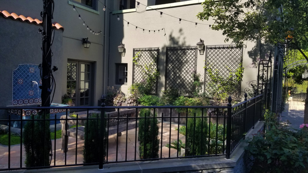 Geometrischer, Halbschattiger Mediterraner Garten im Innenhof im Sommer mit Wasserspiel, Natursteinplatten und Metallzaun in Seattle