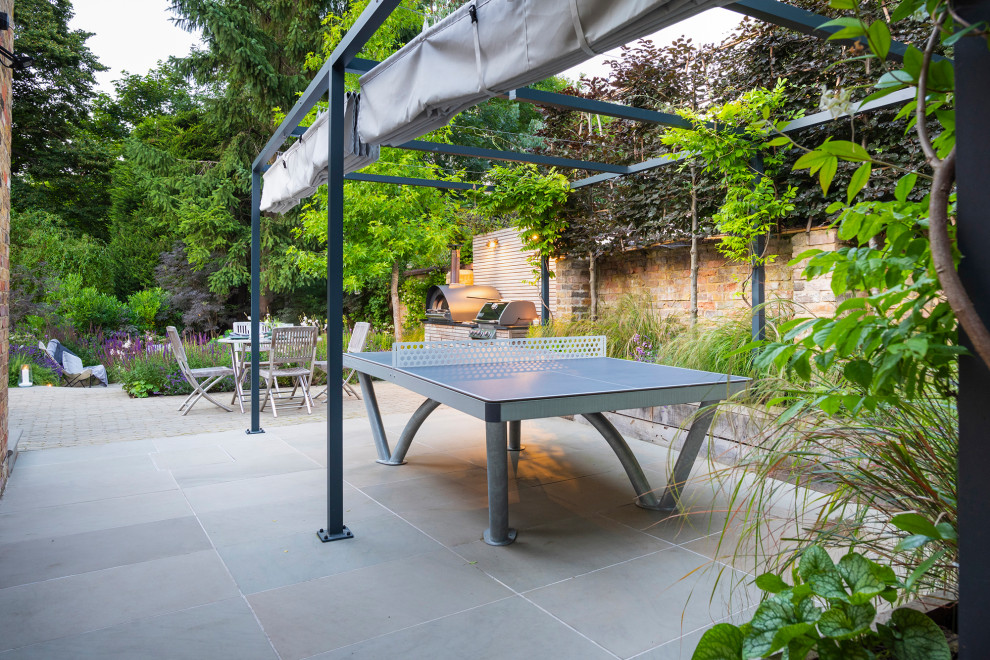 Inspiration pour une terrasse latérale traditionnelle avec une cuisine d'été, des pavés en pierre naturelle et un gazebo ou pavillon.
