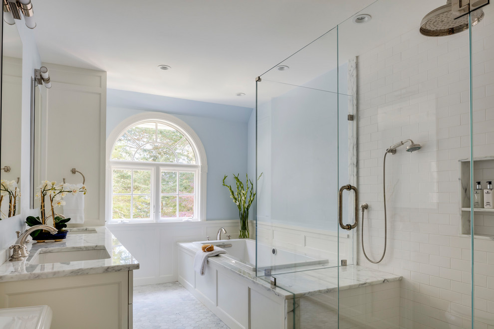 This is an example of a mid-sized transitional master bathroom in Boston with recessed-panel cabinets, white cabinets, a corner tub, an alcove shower, a one-piece toilet, blue walls, mosaic tile floors, marble benchtops, multi-coloured floor and a hinged shower door.
