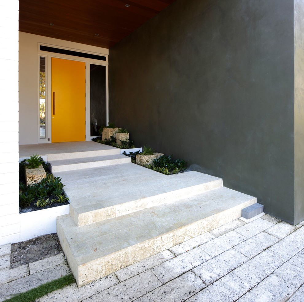 Design ideas for a mid-sized contemporary front door in Miami with green walls, limestone floors, a single front door, a yellow front door and beige floor.