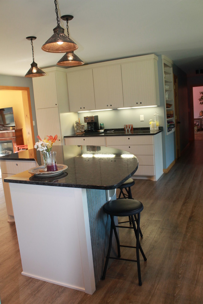 This is an example of a mid-sized country l-shaped eat-in kitchen in Minneapolis with a farmhouse sink, flat-panel cabinets, white cabinets, granite benchtops, stainless steel appliances and with island.