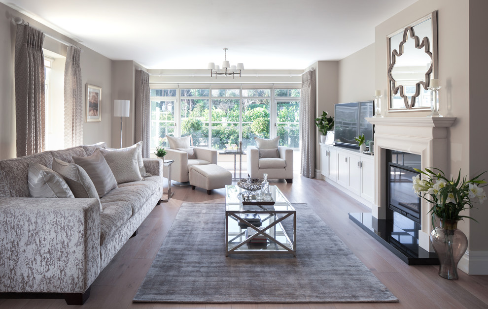 This is an example of a large transitional formal enclosed living room in Dublin with beige walls, medium hardwood floors, a standard fireplace, a built-in media wall, brown floor and a stone fireplace surround.
