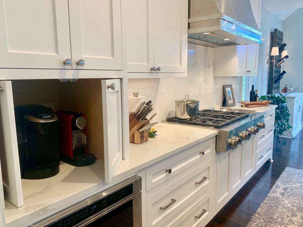 Eat-in kitchen - large transitional l-shaped medium tone wood floor and brown floor eat-in kitchen idea with an undermount sink, recessed-panel cabinets, white cabinets, quartz countertops, white backsplash, stone slab backsplash, stainless steel appliances, an island and white countertops