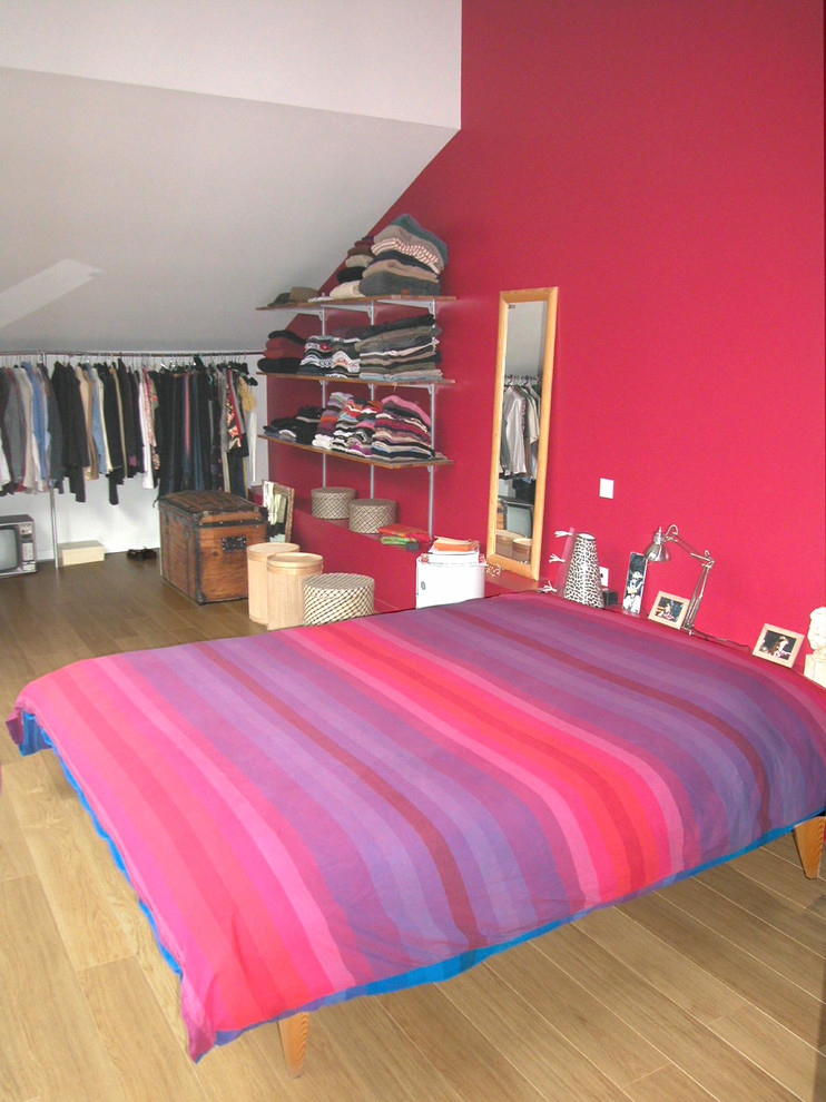 Photo of an industrial master bedroom in Lyon with red walls and light hardwood floors.