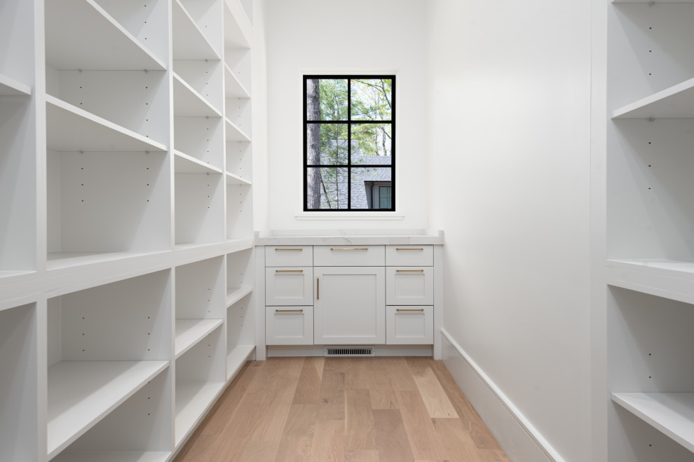 Kitchen - mid-sized transitional u-shaped light wood floor kitchen idea with an undermount sink, shaker cabinets, black cabinets, quartz countertops, white backsplash, quartz backsplash, stainless steel appliances, an island and black countertops