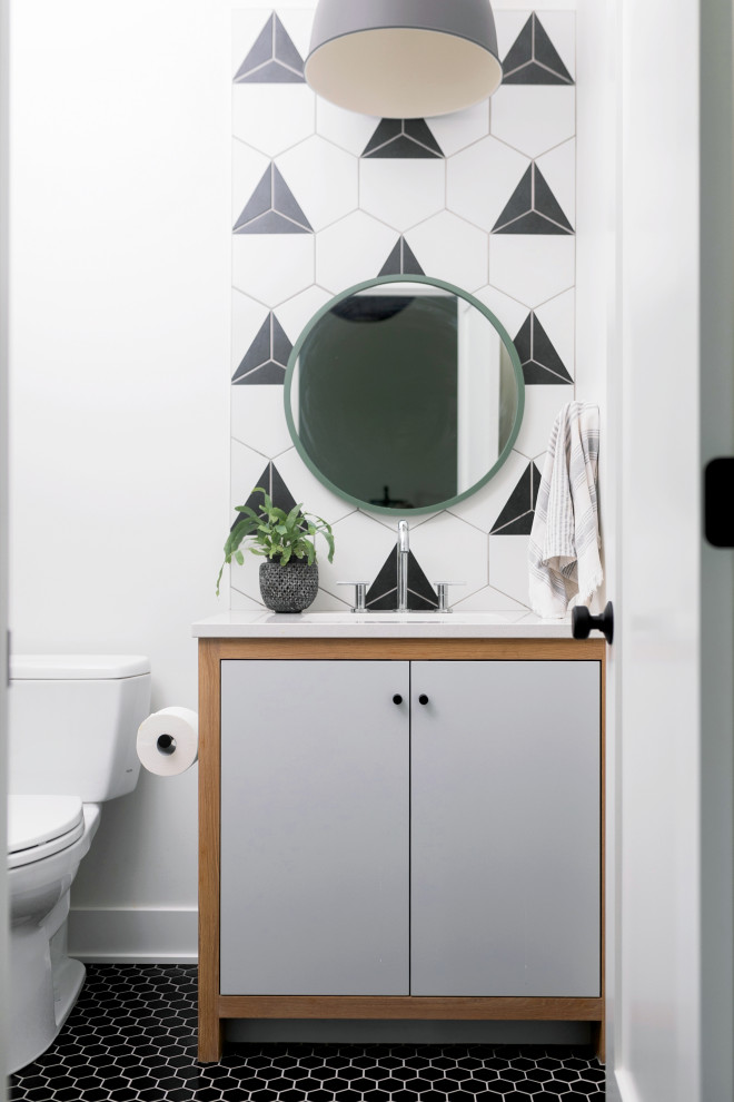 Contemporary powder room in Grand Rapids with flat-panel cabinets, medium wood cabinets, a two-piece toilet, black and white tile, white walls, mosaic tile floors, an undermount sink, engineered quartz benchtops, black floor, white benchtops and a built-in vanity.