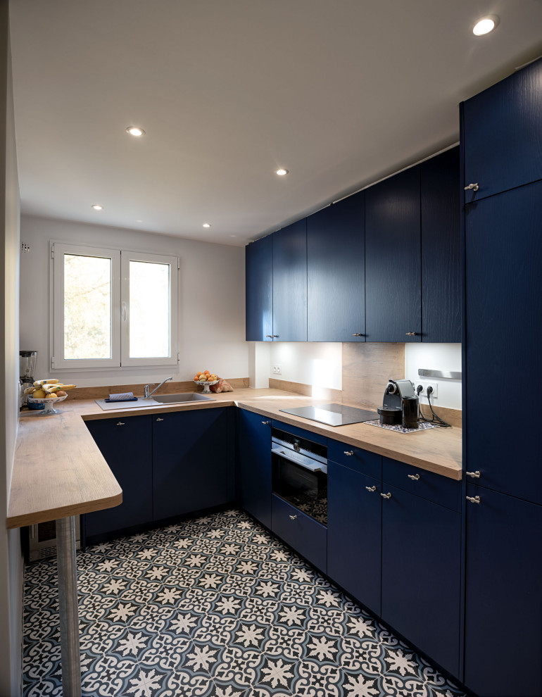 Inspiration for a traditional u-shaped enclosed kitchen in Paris with a submerged sink, blue cabinets, wood worktops, brown splashback, wood splashback, integrated appliances, cement flooring, no island, blue floors and brown worktops.