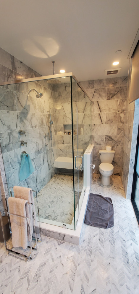 Photo of a large modern ensuite bathroom in New York with glass-front cabinets, white cabinets, a freestanding bath, a corner shower, a one-piece toilet, grey tiles, marble tiles, grey walls, marble flooring, a submerged sink, engineered stone worktops, grey floors, a hinged door, white worktops, a shower bench, double sinks, a floating vanity unit and a coffered ceiling.