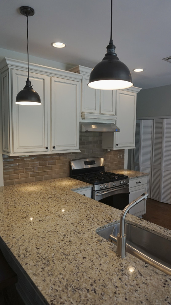 Inspiration for a large transitional u-shaped medium tone wood floor eat-in kitchen remodel in Atlanta with an undermount sink, raised-panel cabinets, white cabinets, granite countertops, gray backsplash, ceramic backsplash, stainless steel appliances and an island
