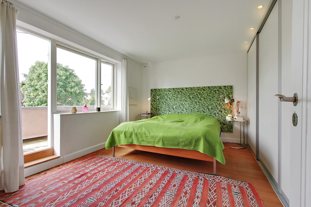 Mid-sized eclectic master bedroom in Wiltshire with white walls, medium hardwood floors and no fireplace.