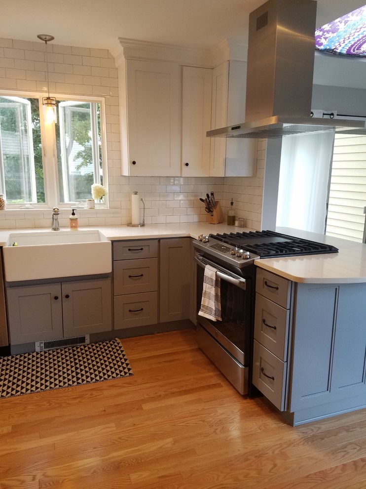 Inspiration for a small transitional light wood floor and beige floor kitchen remodel in Providence with a farmhouse sink, shaker cabinets, white cabinets, marble countertops, white backsplash, subway tile backsplash, white countertops and stainless steel appliances