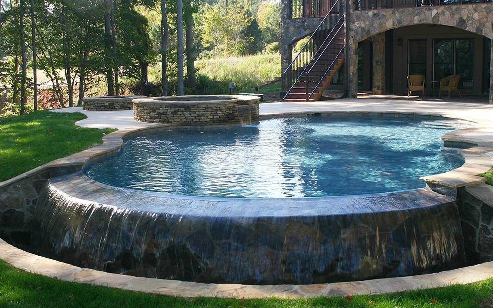 Mid-sized transitional backyard concrete paver and custom-shaped infinity hot tub photo in Charlotte