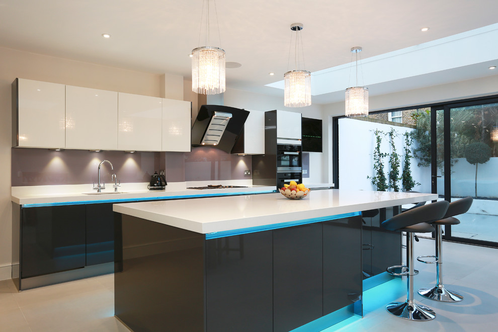 This is an example of an expansive contemporary eat-in kitchen in London with an undermount sink, grey cabinets, glass sheet splashback, stainless steel appliances, ceramic floors and with island.