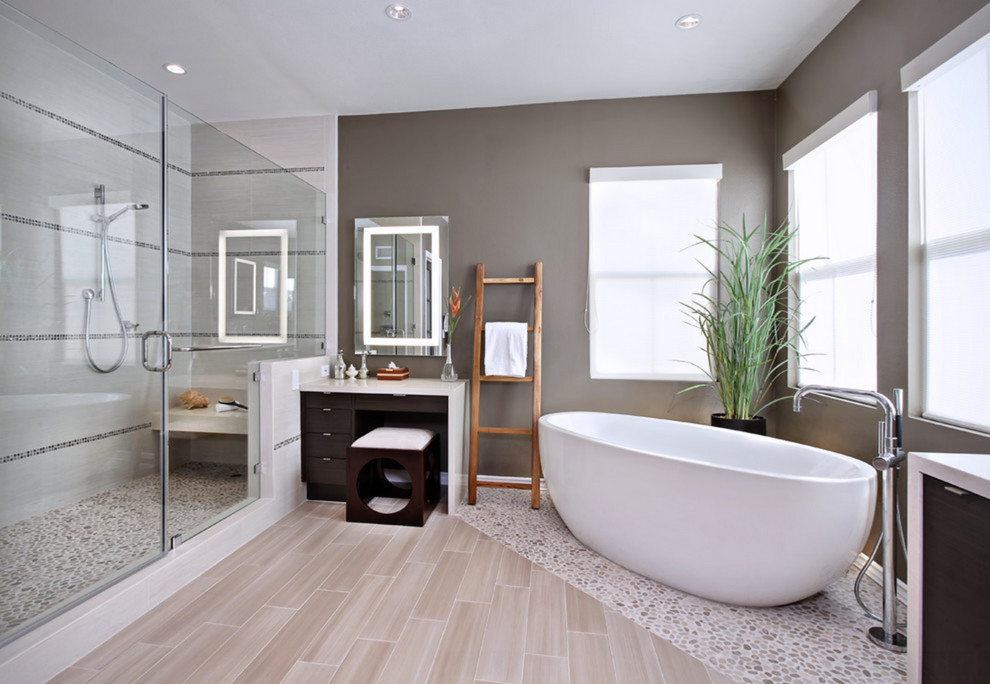 Design ideas for a contemporary bathroom in Orange County with flat-panel cabinets, dark wood cabinets, a freestanding tub, an alcove shower, beige tile, pebble tile, grey walls and pebble tile floors.