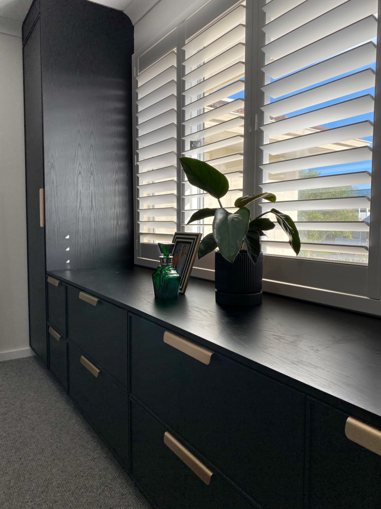 Photo of a mid-sized gender-neutral walk-in wardrobe in Perth with black cabinets, carpet and grey floor.