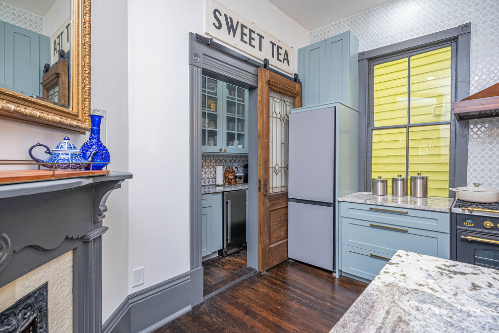 Large transitional galley dark wood floor and black floor kitchen pantry photo with a farmhouse sink, shaker cabinets, blue cabinets, granite countertops, blue backsplash, ceramic backsplash, black appliances, an island and white countertops