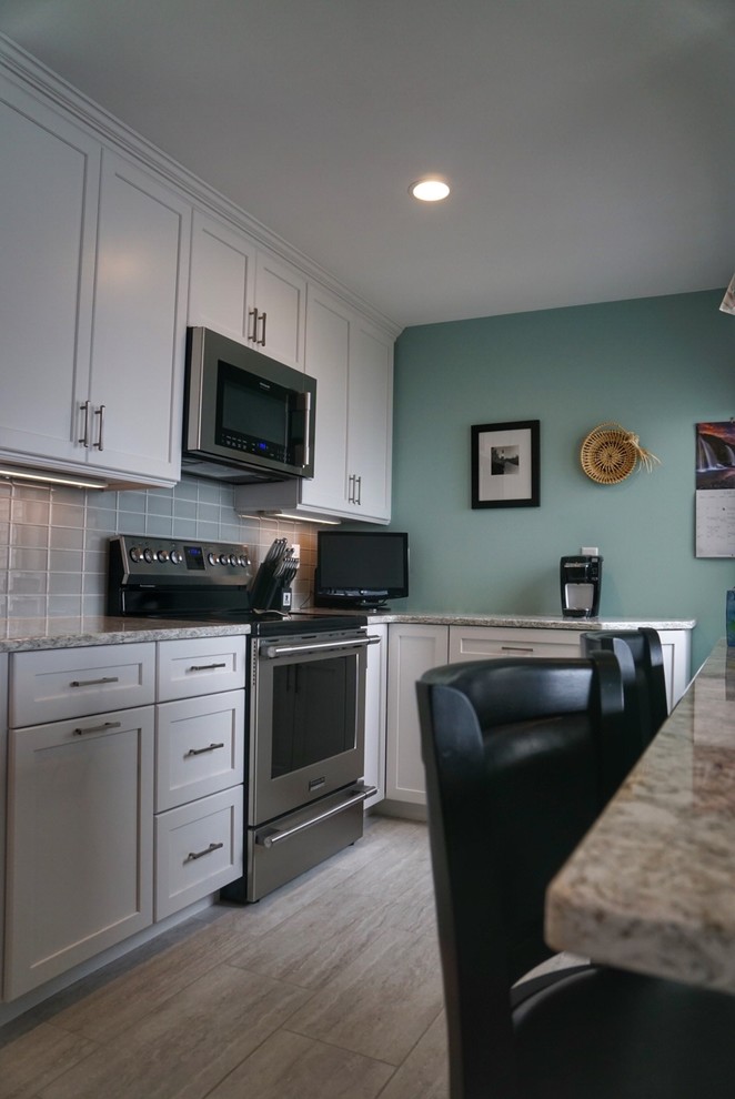 Example of a small transitional galley porcelain tile and gray floor eat-in kitchen design in Boston with a single-bowl sink, shaker cabinets, white cabinets, quartz countertops, gray backsplash, glass tile backsplash, stainless steel appliances and a peninsula