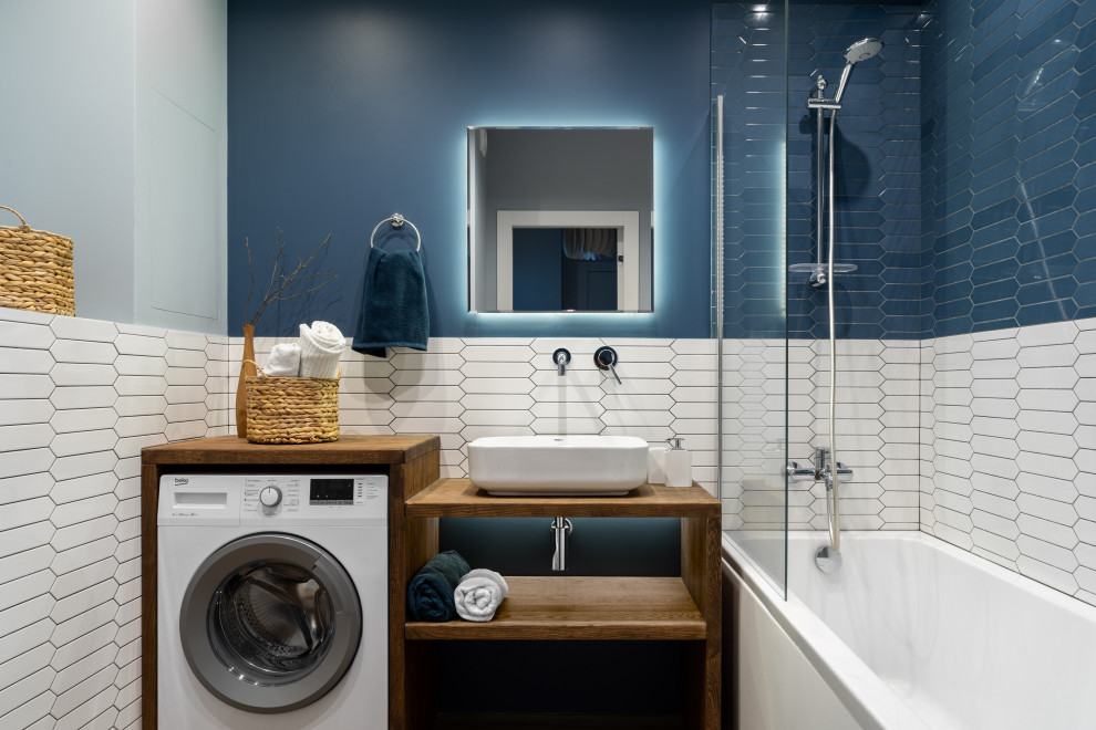 Идея дизайна: главная ванная комната со стиральной машиной в современном стиле с открытыми фасадами, ванной в нише, душем над ванной, белой плиткой, синими стенами, настольной раковиной и тумбой под одну раковину