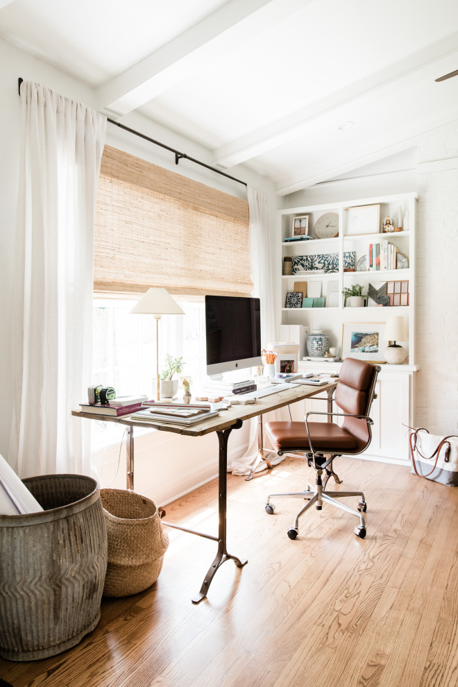 This is an example of a transitional home office in Austin with white walls, light hardwood floors, a freestanding desk, beige floor and vaulted.