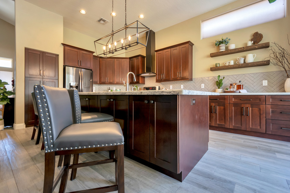 Inspiration for a mid-sized transitional l-shaped porcelain tile and brown floor open concept kitchen remodel in Phoenix with a single-bowl sink, shaker cabinets, brown cabinets, granite countertops, gray backsplash, brick backsplash, stainless steel appliances, an island and multicolored countertops