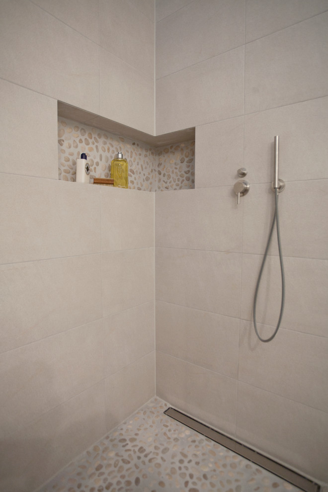 Ispirazione per una stanza da bagno con doccia design di medie dimensioni con doccia a filo pavimento, WC sospeso, piastrelle grigie, piastrelle in ceramica, pareti bianche, pavimento con piastrelle di ciottoli e lavabo a bacinella