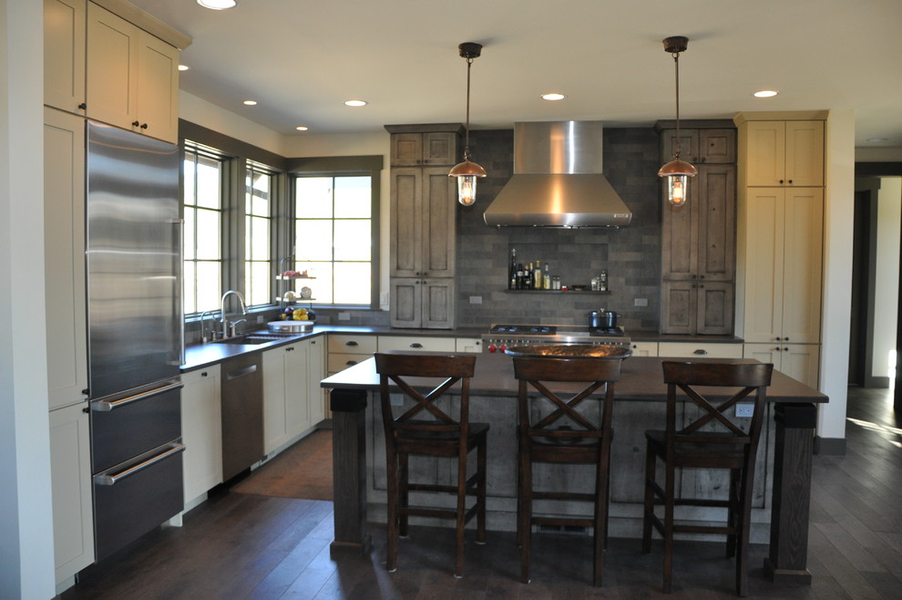 Example of a large mountain style l-shaped medium tone wood floor eat-in kitchen design in Seattle with an undermount sink, shaker cabinets, distressed cabinets, quartz countertops, gray backsplash, stone tile backsplash, stainless steel appliances and an island