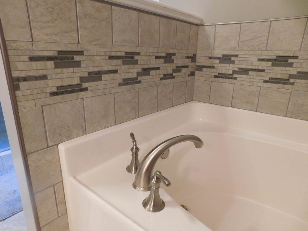 Corner bathtub - large transitional master gray tile and ceramic tile ceramic tile corner bathtub idea with raised-panel cabinets, medium tone wood cabinets, a two-piece toilet, beige walls, an undermount sink and granite countertops