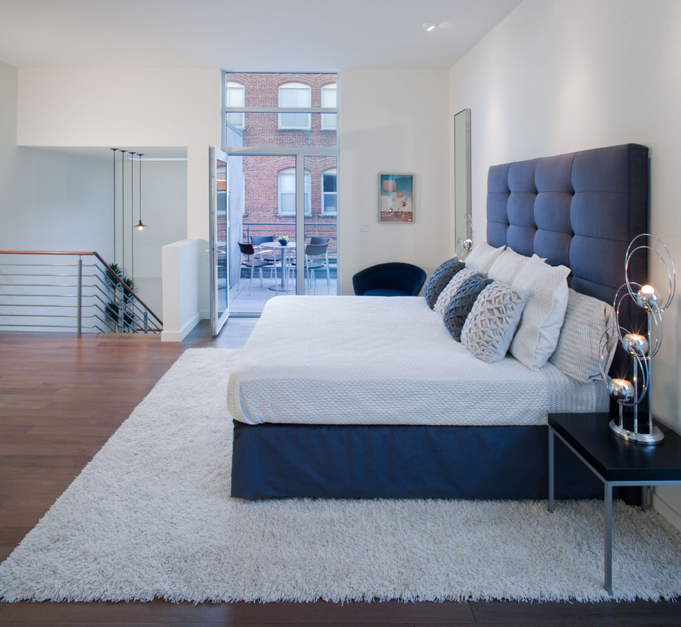 Photo of a transitional loft-style bedroom in Los Angeles with white walls, dark hardwood floors and no fireplace.