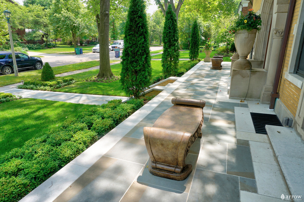 Photo of a large traditional front yard patio with natural stone pavers.