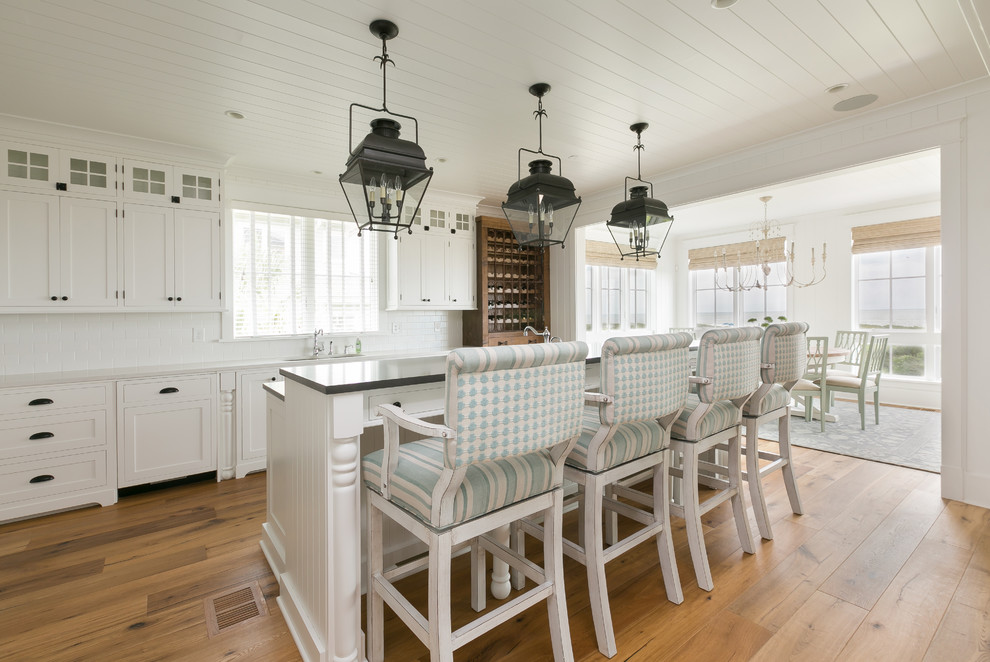 Beach style light wood floor kitchen photo in Charleston with an undermount sink, shaker cabinets, white cabinets, white backsplash, ceramic backsplash and an island