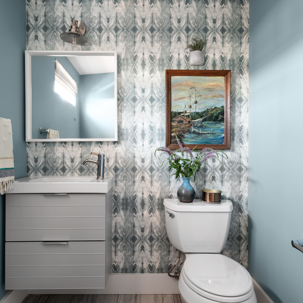 На фото: туалет в стиле неоклассика (современная классика) с плоскими фасадами, серыми фасадами, разноцветными стенами, консольной раковиной, коричневым полом, белой столешницей, подвесной тумбой и обоями на стенах