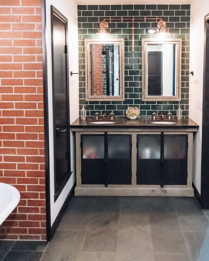 Industrial bathroom in Other with a freestanding tub, ceramic floors, an undermount sink, grey floor, black benchtops, a double vanity, a freestanding vanity, brick walls, green tile and subway tile.