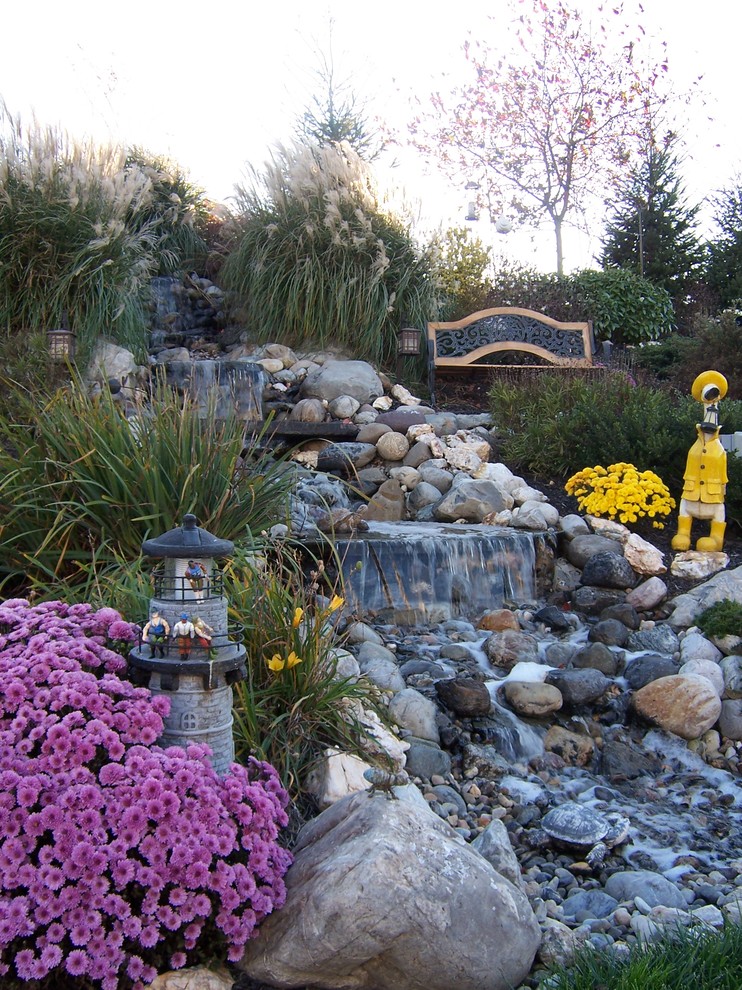 Inspiration for a traditional backyard garden in Other with a water feature.