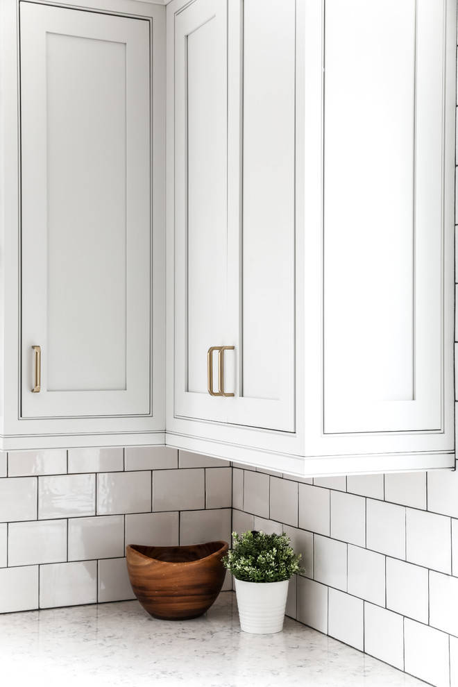 Inspiration for a transitional l-shaped medium tone wood floor and brown floor eat-in kitchen remodel in Boston with a farmhouse sink, beaded inset cabinets, white cabinets, quartz countertops, white backsplash, subway tile backsplash, stainless steel appliances, an island and gray countertops