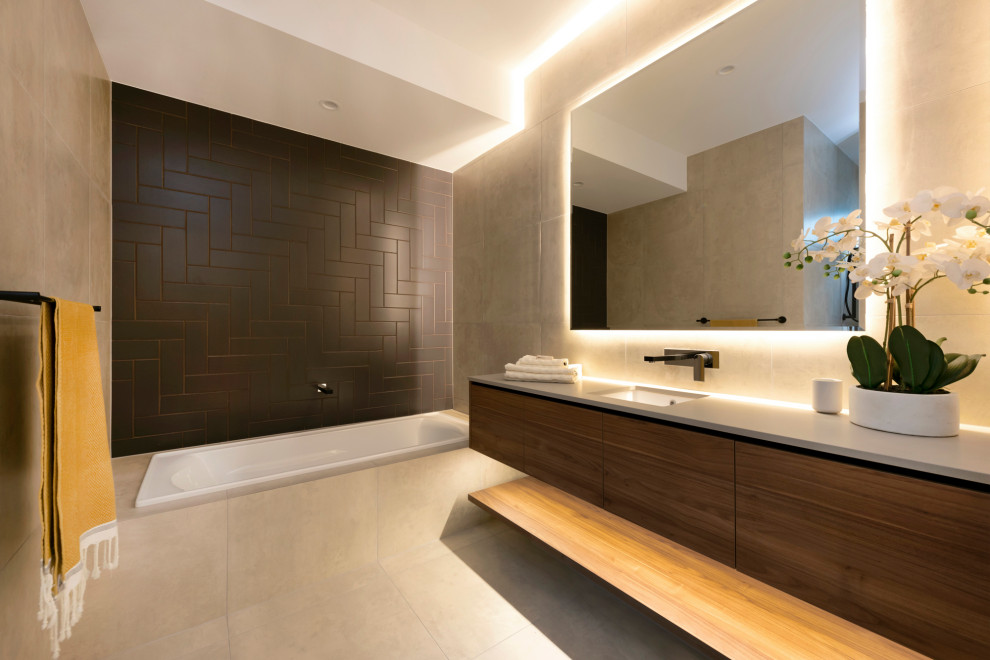 Contemporary bathroom in Brisbane with flat-panel cabinets, dark wood cabinets, a drop-in tub, black tile, grey walls, an undermount sink, grey floor and grey benchtops.