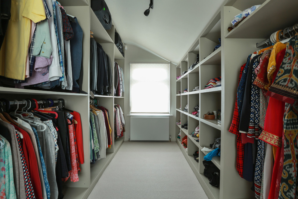 Inspiration for a mid-sized contemporary gender-neutral walk-in wardrobe in London with open cabinets, carpet and beige floor.